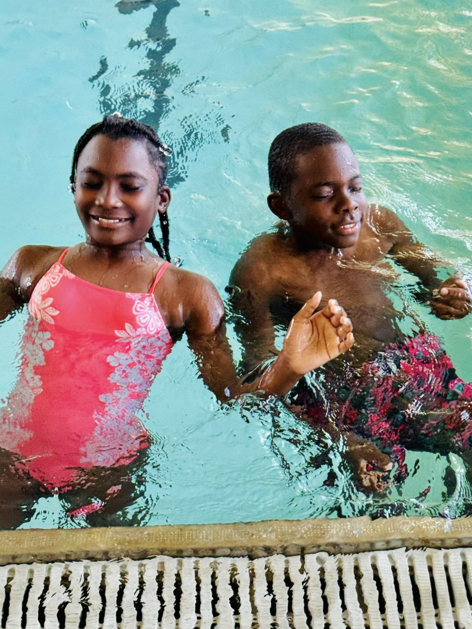 A girl and a boy in a swimming pool.